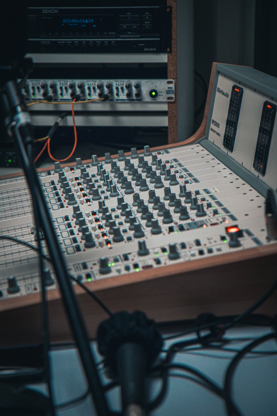 Console de mixage audio avec faders et boutons éclairés dans un studio.