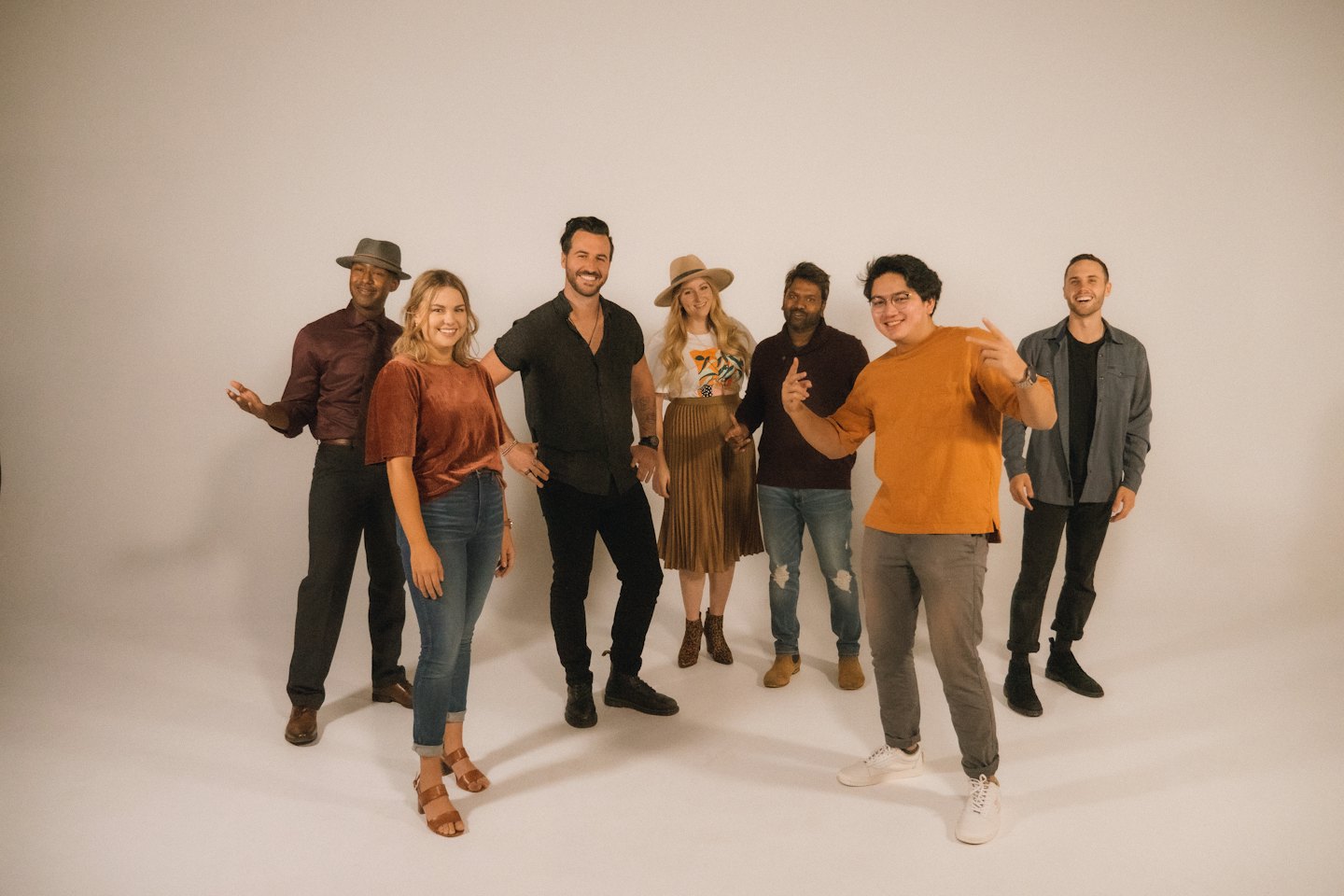Six personnes souriantes se tiennent ensemble devant un mur blanc.