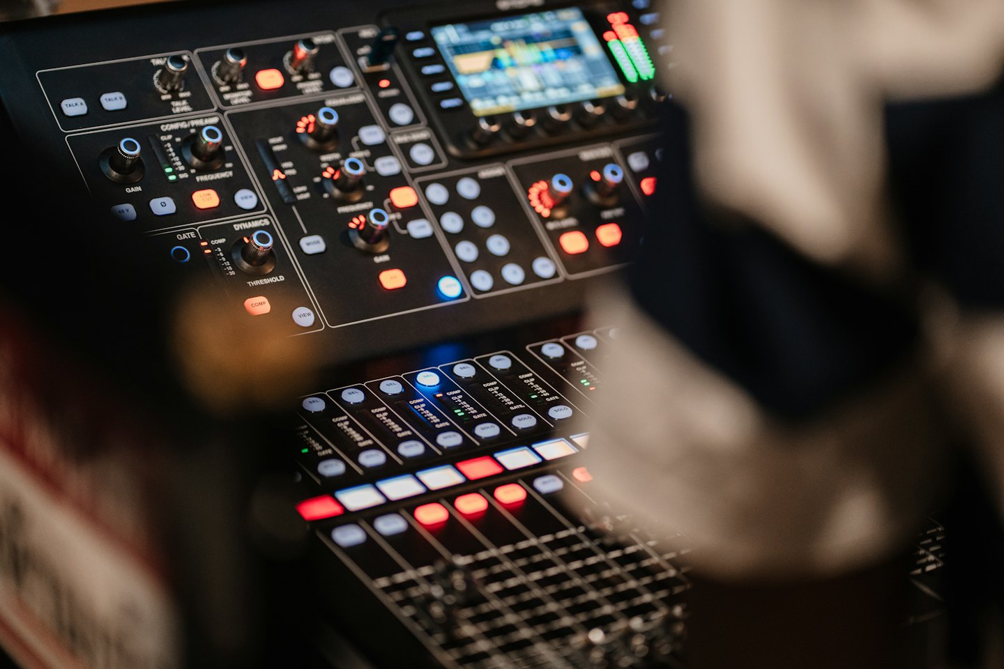Table de mixage audio numérique avec boutons et faders lumineux.